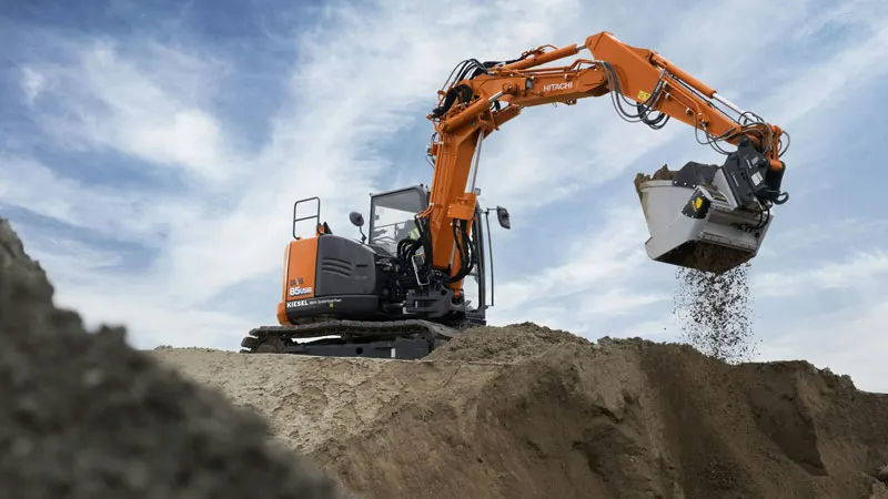 An orange and black excavator on top of a hill